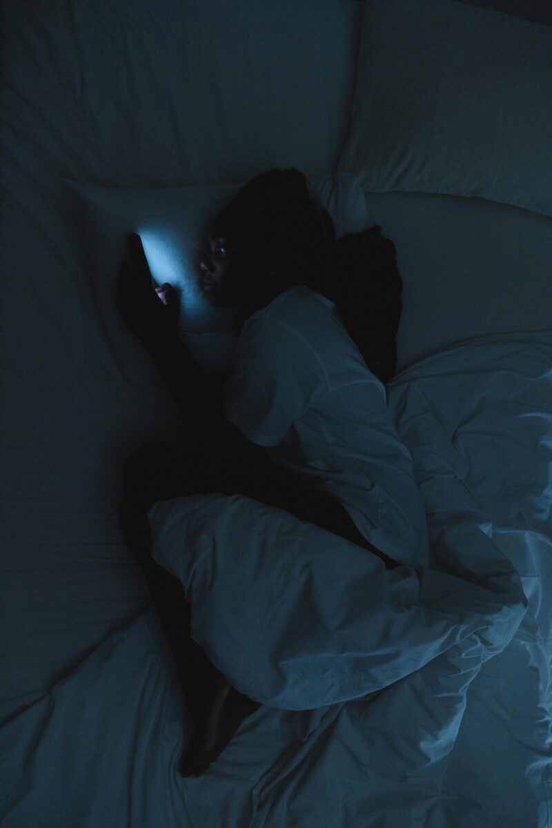 Woman struggling to sleep on her phone laying in bed