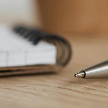 A desk, notebook, and pen utilized to document medication interactions and choose pharmacological interventions for mental health
